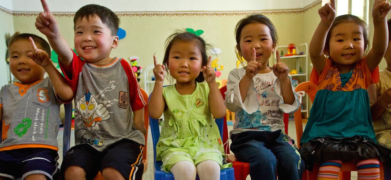 Children raising hands in celebration in a classroom